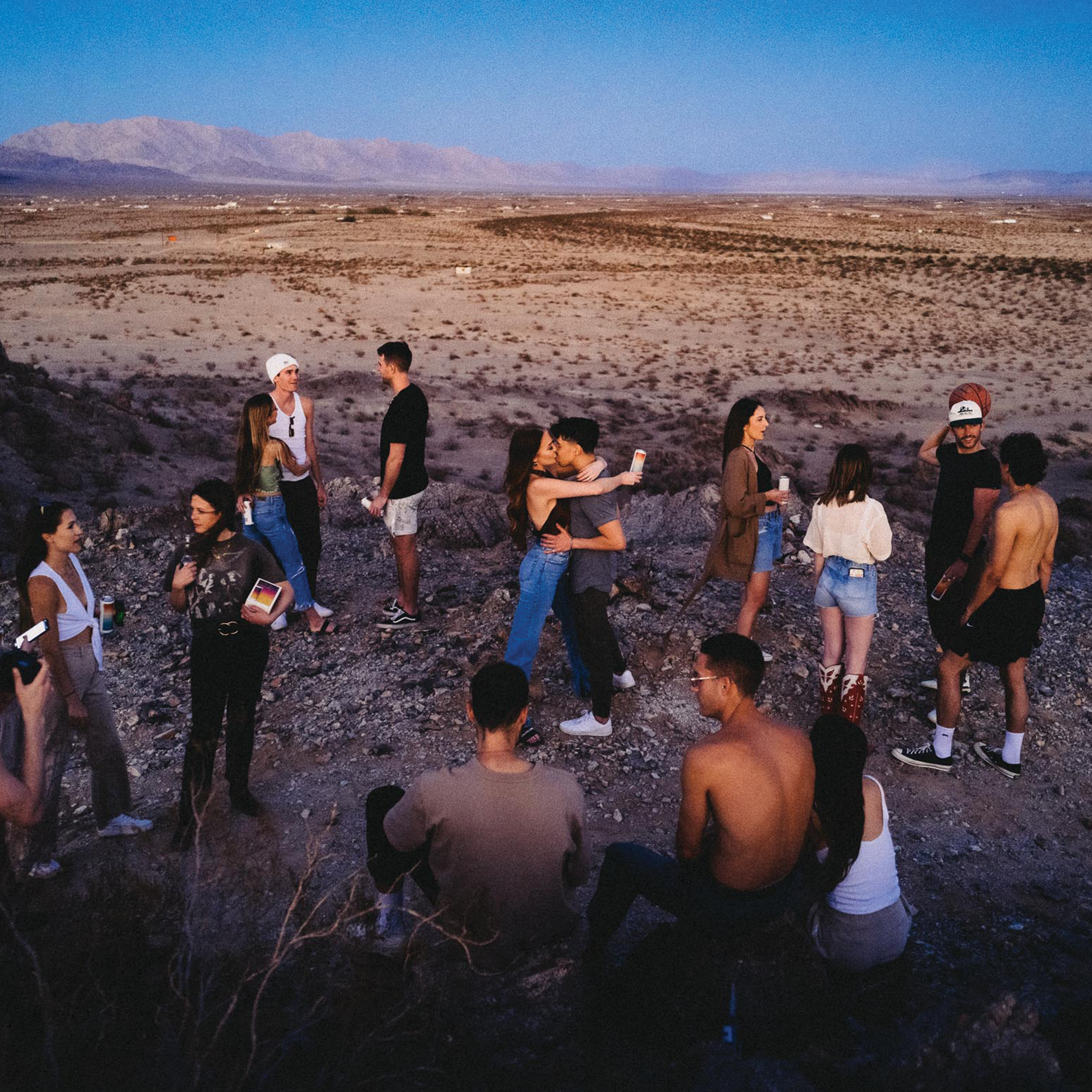 friends enjoying hiyo while talking, embracing, and enjoying the view of a desert at sunset.