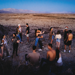 friends enjoying hiyo while talking, embracing, and enjoying the view of a desert at sunset.