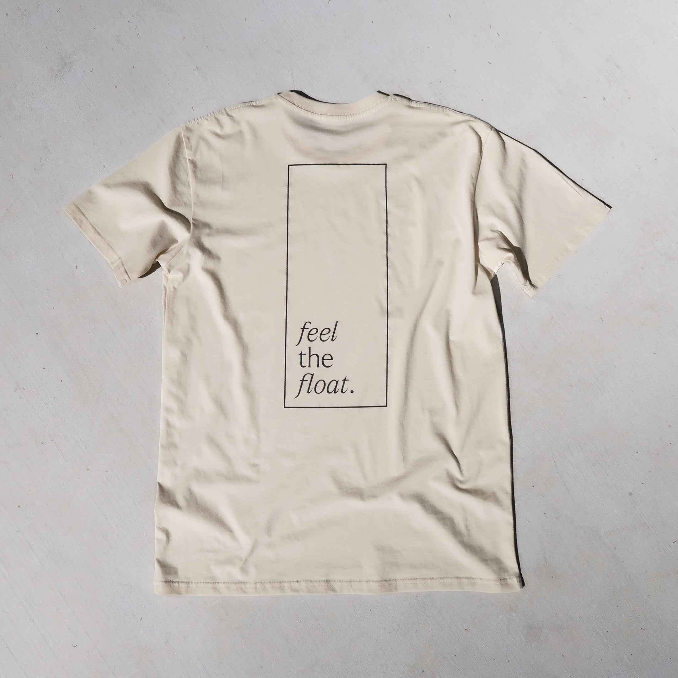 a cream t-shirt with 'feel the float' inside a rectangle printed across the full back.