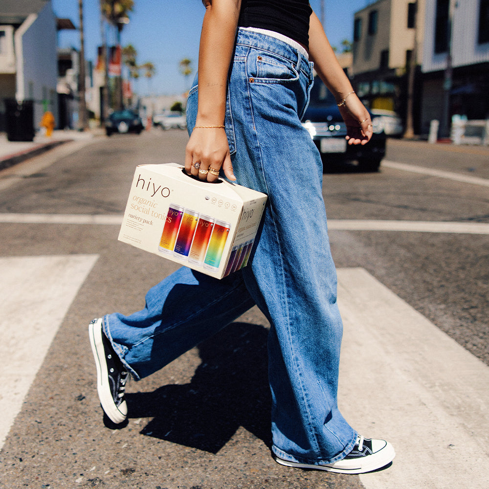 Person holding a non-alcoholic functional seltzer hiyo variety pack box on a city street