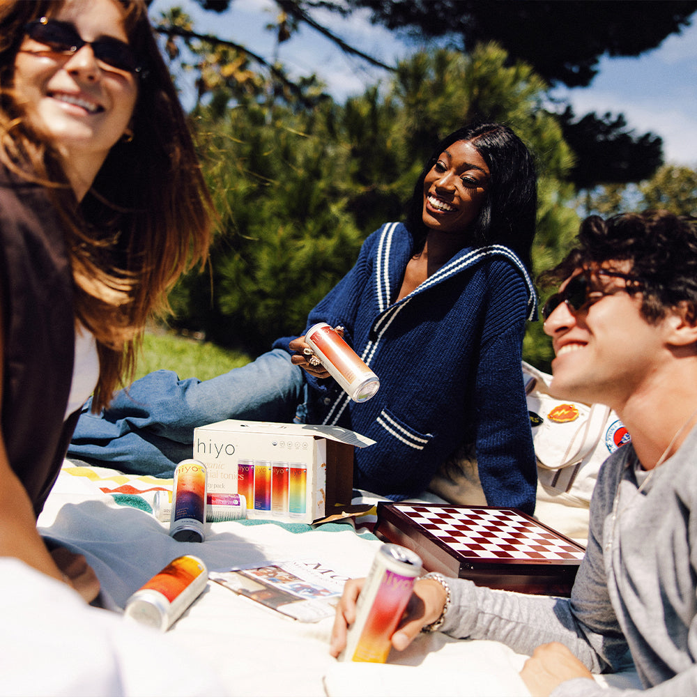 Three friends enjoying a picnic with outdoor games and non-alcoholic functional seltzer hiyo.