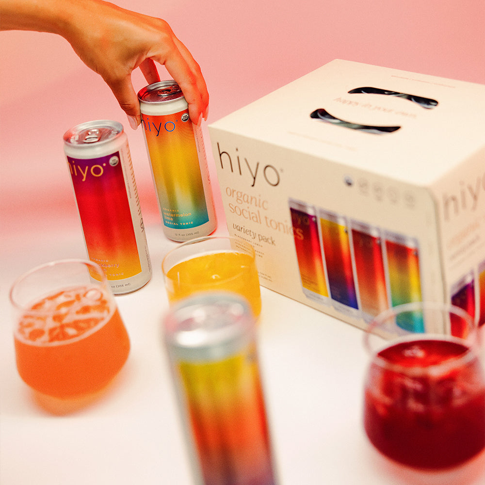 hiyo organic social tonic cans and glasses on a pink background