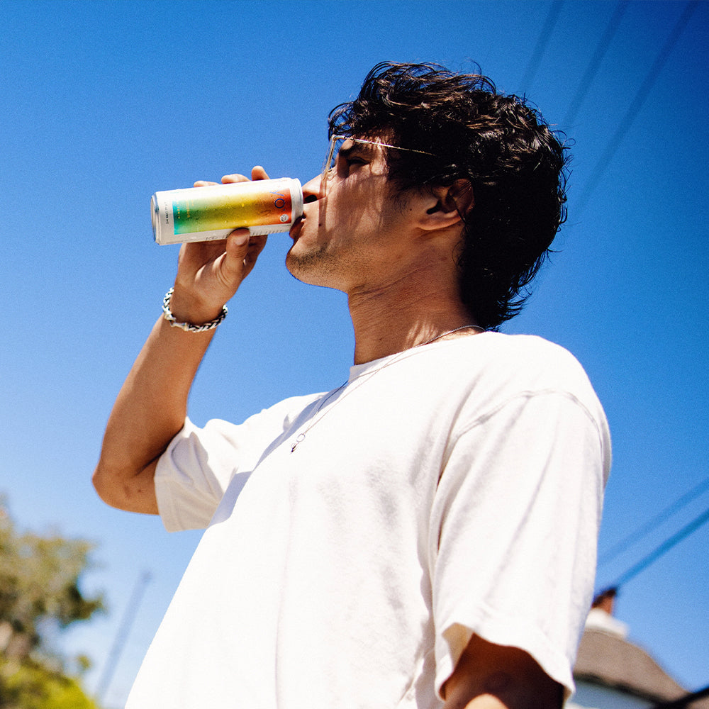 Person drinking non-alcoholic functional seltzer hiyo against a clear blue sky